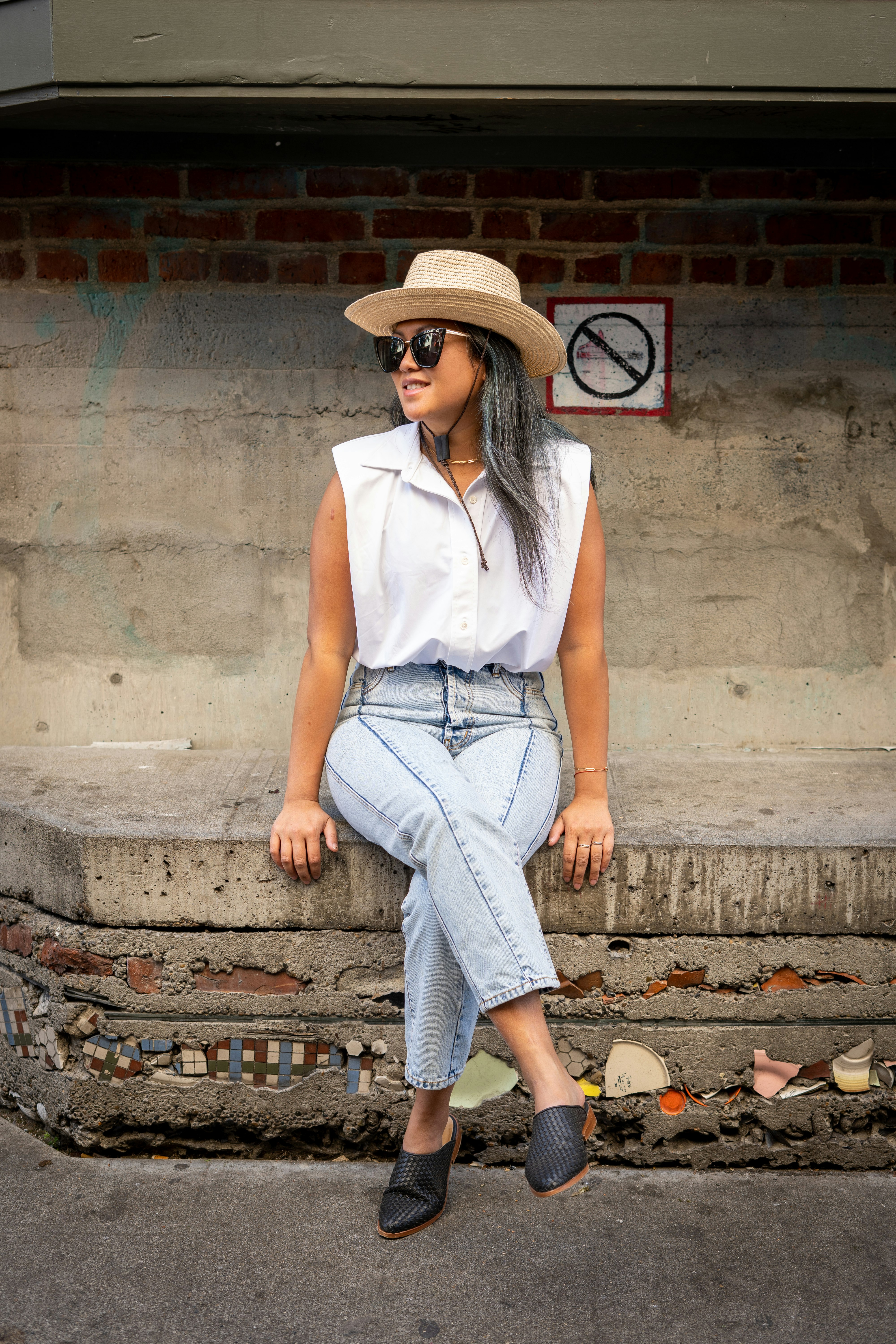 woman in white sleeveless shirt and blue denim jeans sitting on concrete stairs